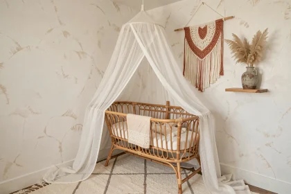 Coin de chambre bébé bohème chic avec berceau en rotin, suspension macramé et décoration en herbes de pampa dans des tons chauds naturels
